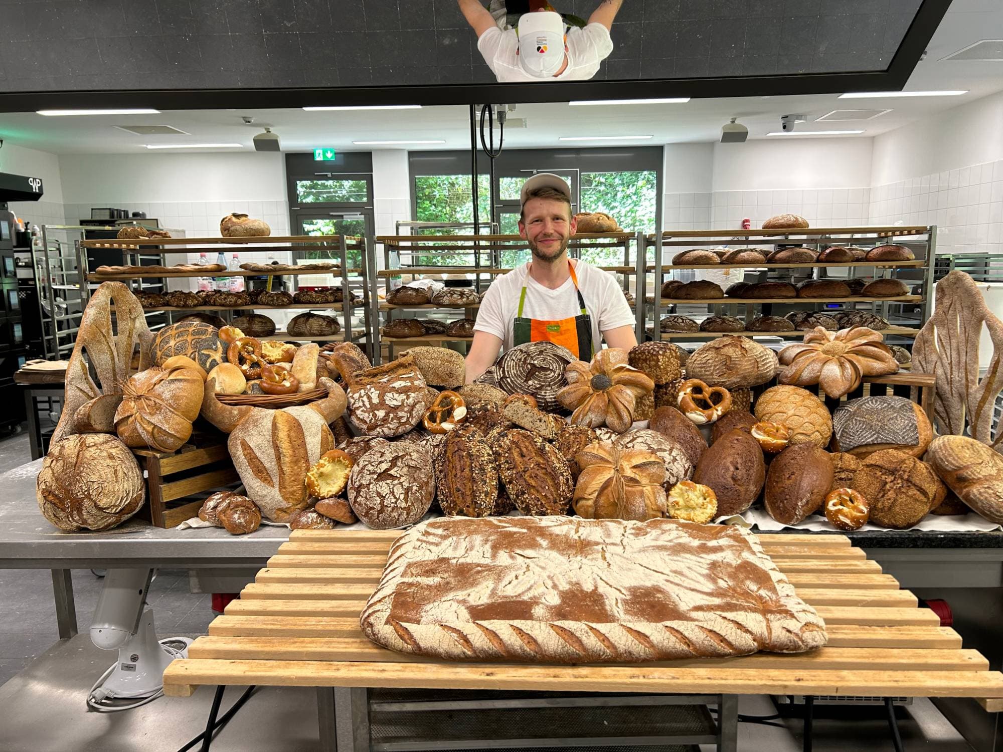 Alex Pelkmann hinter einem Tisch voller Brote bei einem Brotbackseminar der Akademie Deutsches Bäckerhandwerk Weinheim